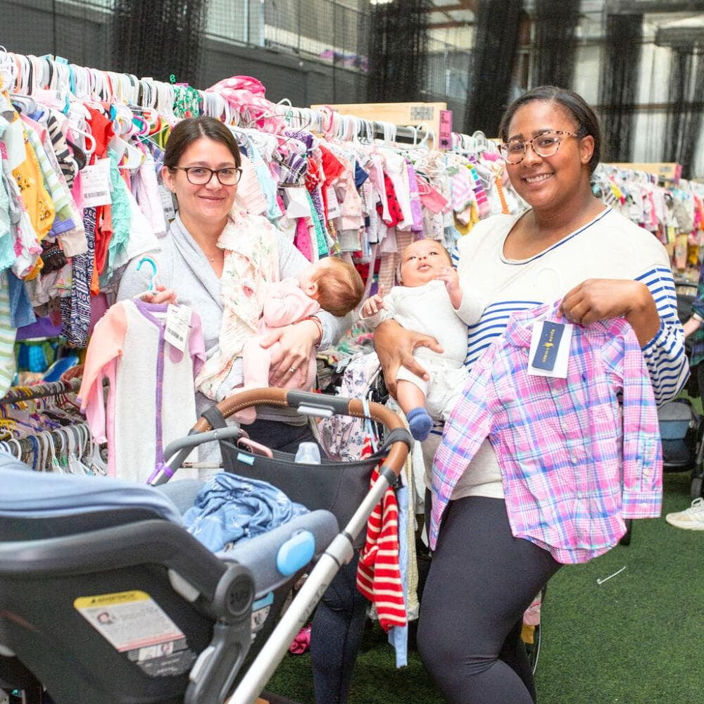 Two mothers hold their babies while shopping.