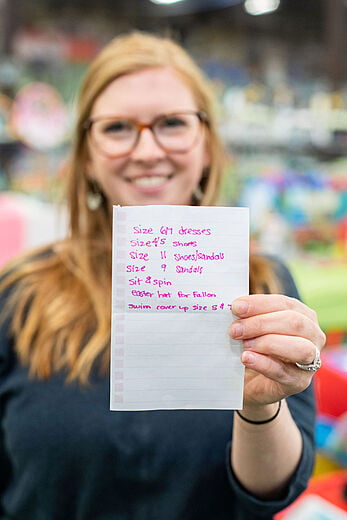 Lady in a green top holds a shopping list